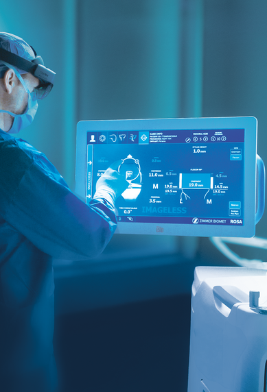 Ein medizinisches Fachpersonal bedient ein interaktives Touchscreen-Display, während ein Roboterarm in der Nähe positioniert ist.