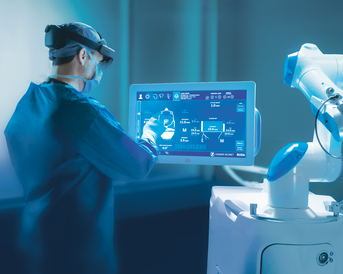 Ein medizinisches Fachpersonal bedient ein interaktives Touchscreen-Display, während ein Roboterarm in der Nähe positioniert ist.