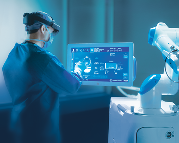 Ein medizinisches Fachpersonal bedient ein interaktives Touchscreen-Display, während ein Roboterarm in der Nähe positioniert ist.