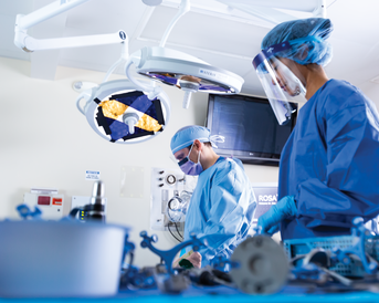 Zwei Chirurgen in OP-Kleidung arbeiten an einem Patienten, umgeben von medizinischen Geräten und Instrumenten in einem Operationssaal.