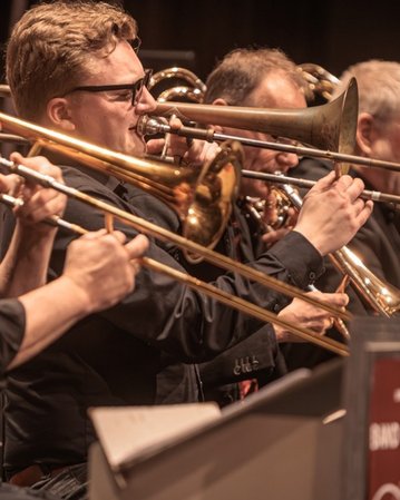 Eine Gruppe von Musikern spielt Posaunen auf einer Bühne während eines Band-Gipfels.